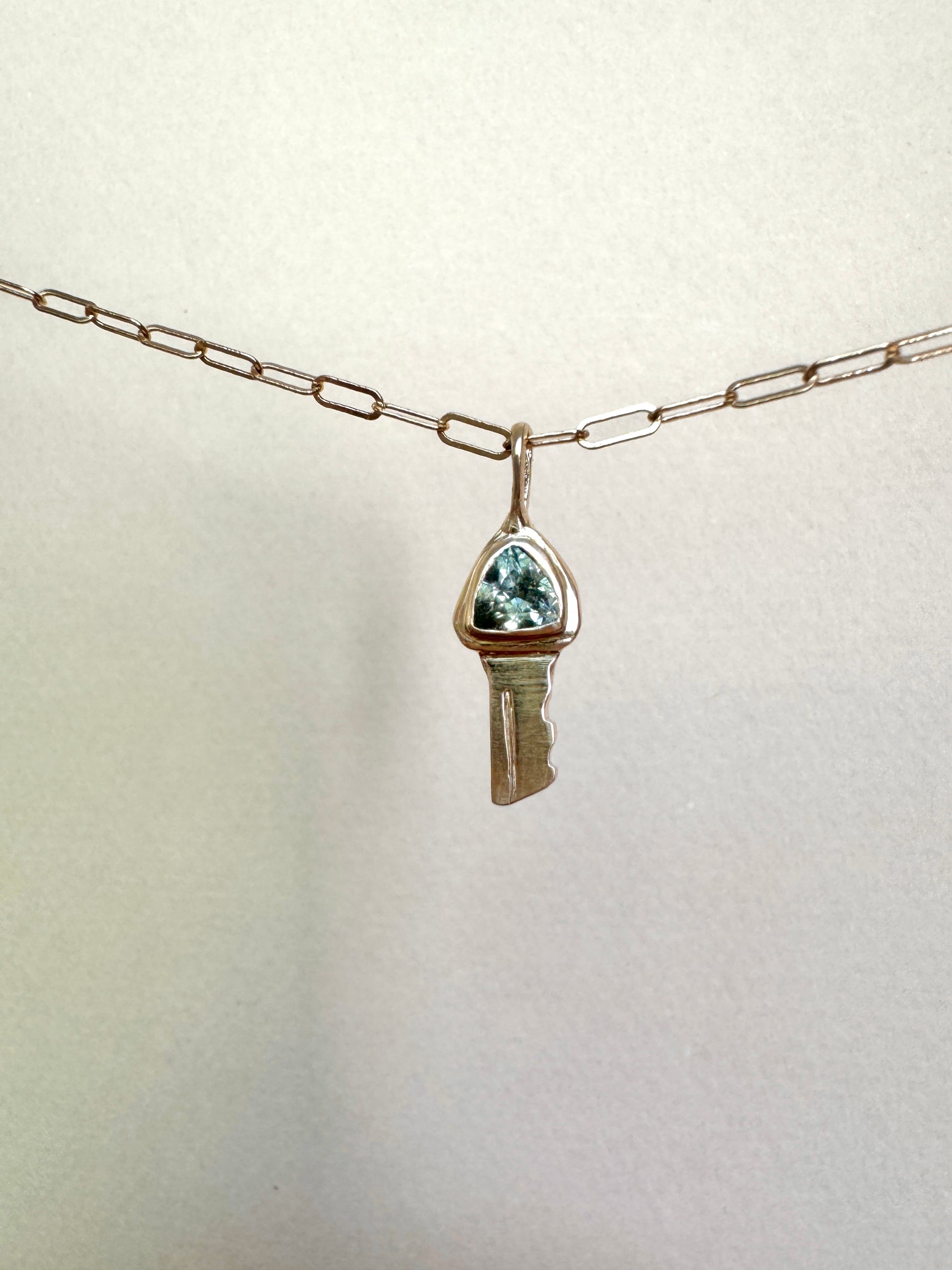 Petite key pendant with teal sapphire in 14k gold by Mellis Fine
